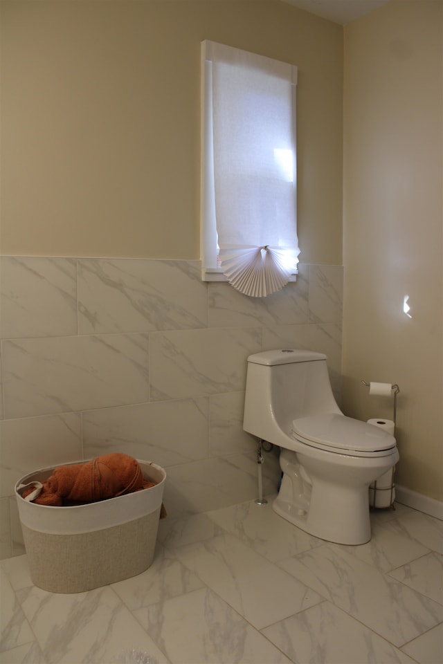 bathroom with toilet and tile walls