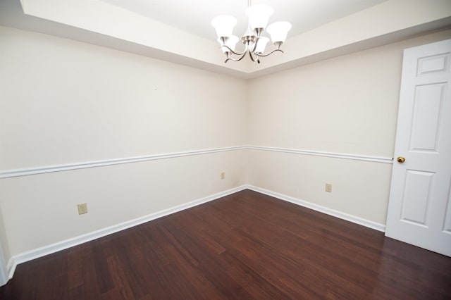 empty room with dark hardwood / wood-style flooring and a notable chandelier