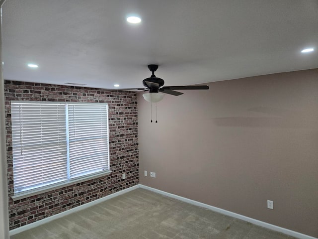 unfurnished room featuring carpet floors, ceiling fan, and brick wall