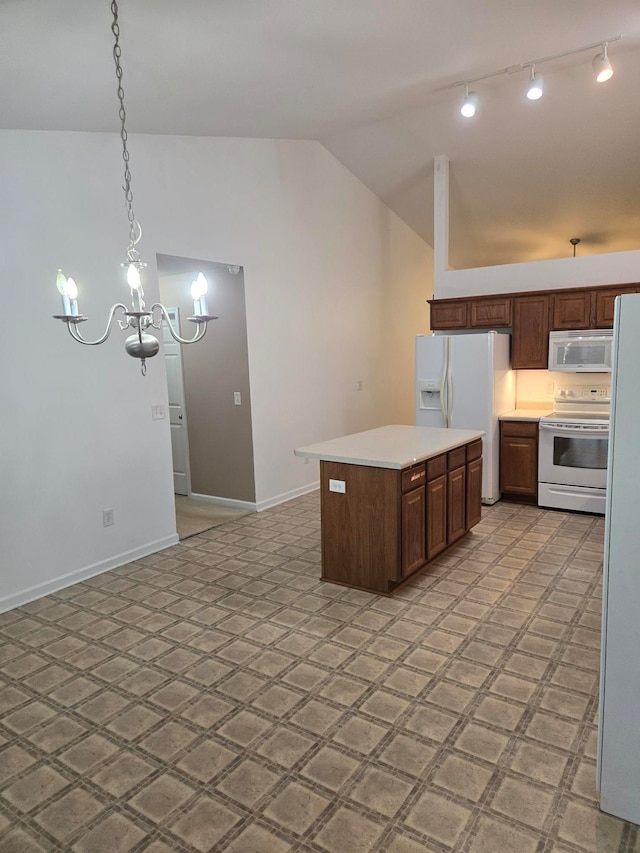 kitchen with pendant lighting, white appliances, vaulted ceiling, a kitchen island, and a chandelier