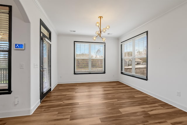 unfurnished dining area with a chandelier, wood-type flooring, and ornamental molding