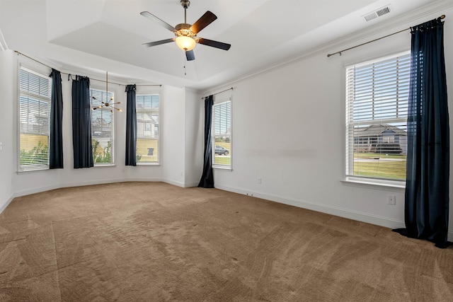 carpeted empty room featuring a raised ceiling, a wealth of natural light, and ceiling fan