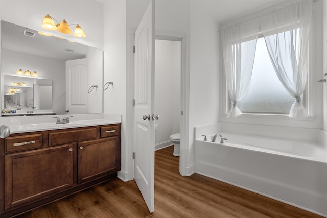 bathroom featuring a bathtub, vanity, wood-type flooring, and toilet