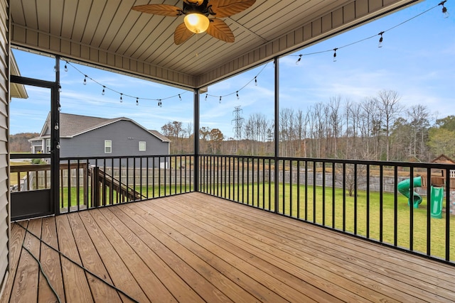 deck featuring a playground, ceiling fan, and a yard