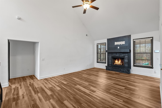 unfurnished living room featuring ceiling fan, a fireplace, high vaulted ceiling, and wood-type flooring