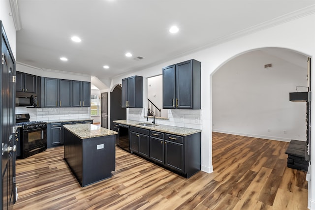 kitchen with light stone countertops, a center island, sink, hardwood / wood-style floors, and black appliances