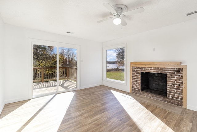 unfurnished living room featuring a fireplace, ceiling fan, hardwood / wood-style floors, and a textured ceiling