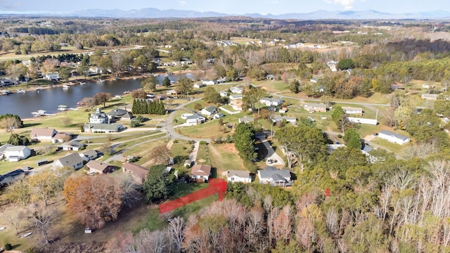 aerial view with a water and mountain view and a view of trees