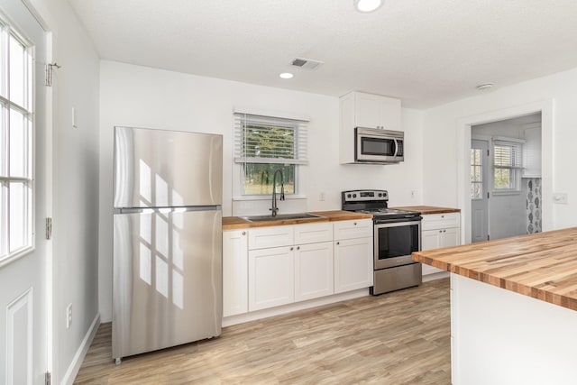 kitchen featuring a sink, wood counters, visible vents, white cabinetry, and appliances with stainless steel finishes