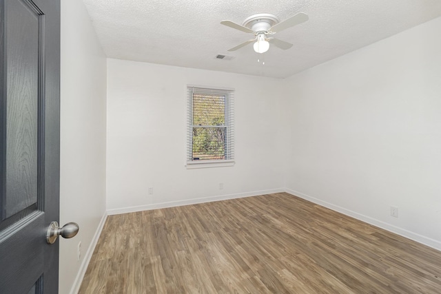 empty room featuring light wood-type flooring, ceiling fan, visible vents, and a textured ceiling