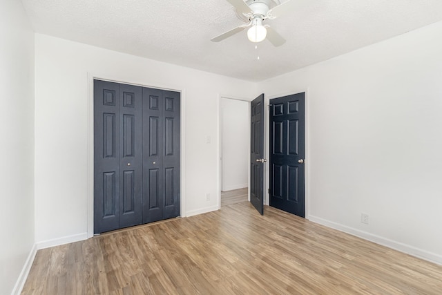 unfurnished bedroom with light wood-style flooring, a closet, baseboards, and a textured ceiling