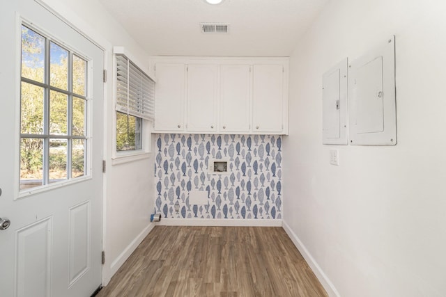 doorway to outside featuring electric panel, wood finished floors, visible vents, and baseboards