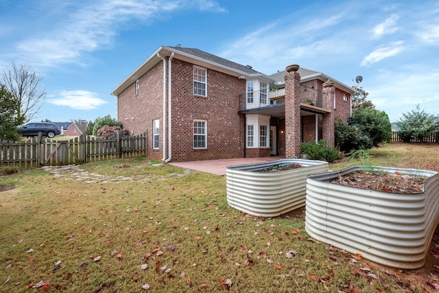 rear view of property with a patio, a balcony, and a lawn