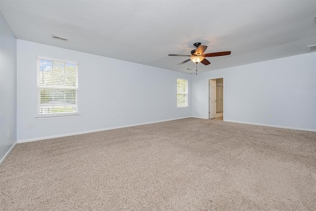 carpeted spare room featuring plenty of natural light and ceiling fan