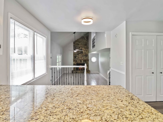 kitchen with light stone countertops, vaulted ceiling, ceiling fan, a fireplace, and hardwood / wood-style floors