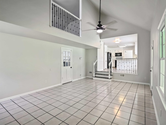 unfurnished living room with light tile patterned floors, high vaulted ceiling, and ceiling fan