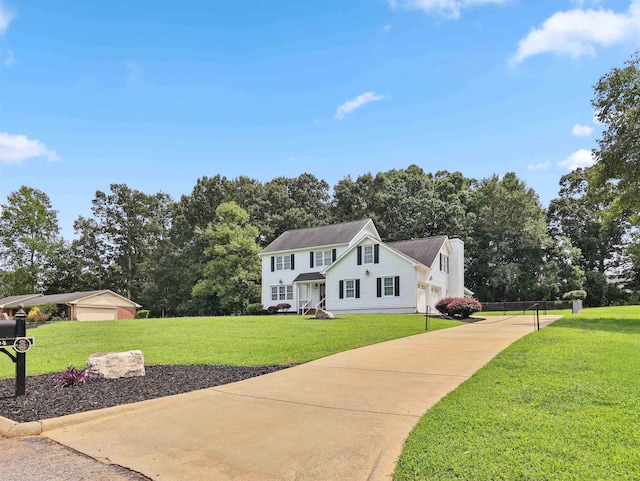 view of front of home with a garage, an outdoor structure, and a front lawn