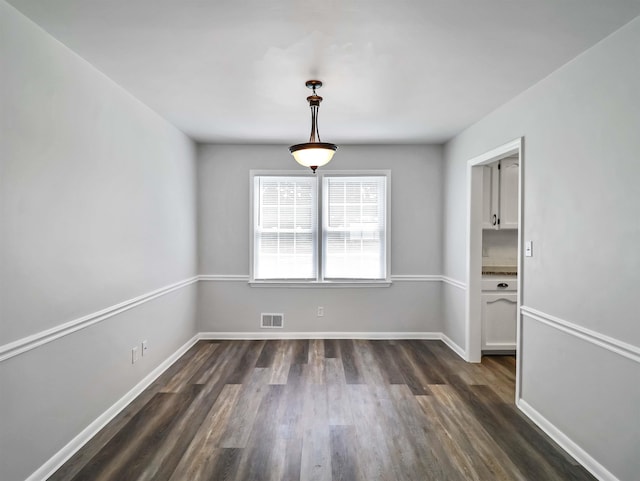 unfurnished dining area featuring dark wood-type flooring