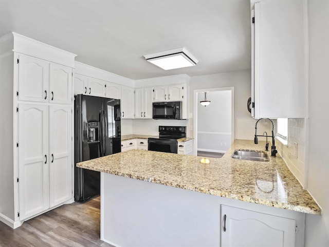 kitchen featuring kitchen peninsula, white cabinetry, sink, and black appliances