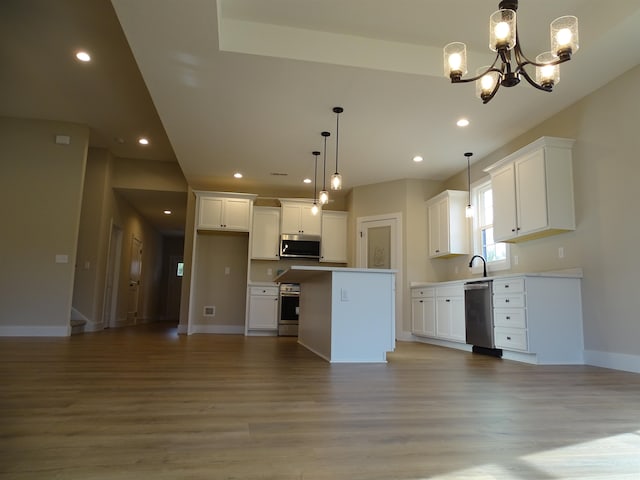 kitchen with stainless steel appliances, decorative light fixtures, an inviting chandelier, white cabinets, and a center island