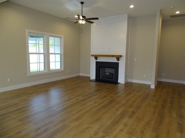 unfurnished living room featuring ceiling fan, a large fireplace, and hardwood / wood-style flooring