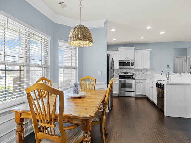 dining space featuring dark wood-type flooring, crown molding, and sink