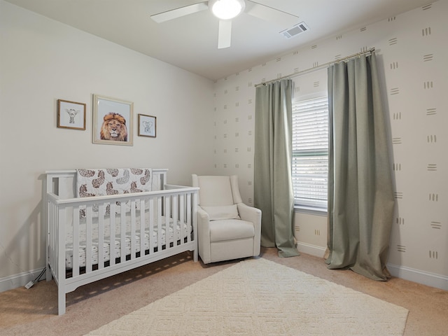 bedroom featuring ceiling fan, light carpet, and a crib