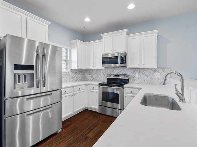 kitchen featuring appliances with stainless steel finishes, dark hardwood / wood-style flooring, light stone counters, sink, and white cabinetry