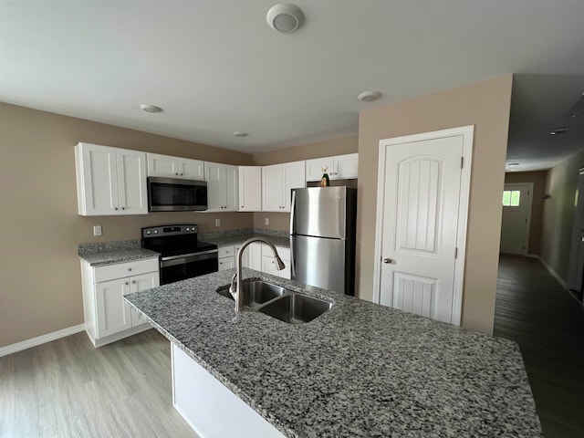 kitchen with white cabinets, sink, light hardwood / wood-style flooring, stone countertops, and stainless steel appliances