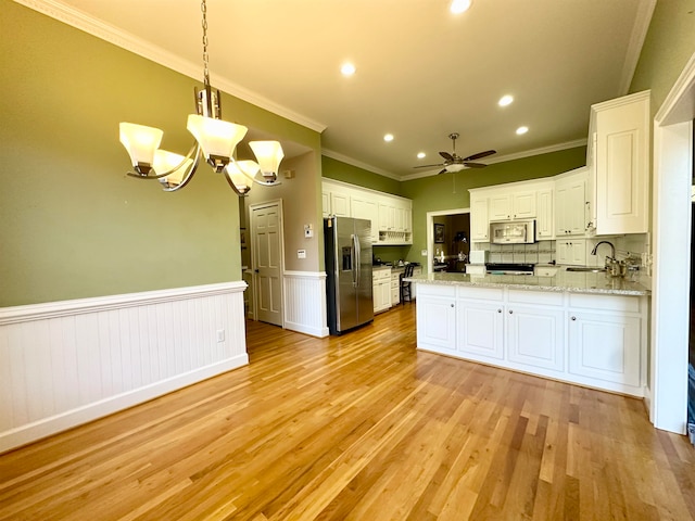 kitchen featuring white cabinets, sink, light wood-type flooring, appliances with stainless steel finishes, and decorative light fixtures