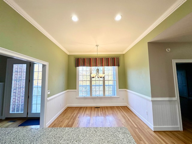 unfurnished dining area featuring hardwood / wood-style floors, a notable chandelier, and ornamental molding