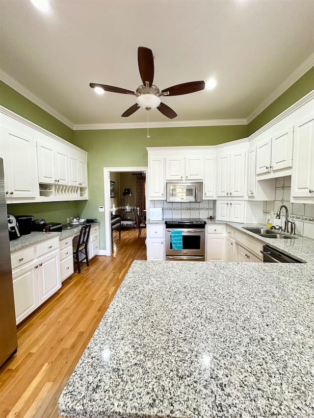 kitchen with white cabinetry, sink, stainless steel appliances, light hardwood / wood-style flooring, and crown molding