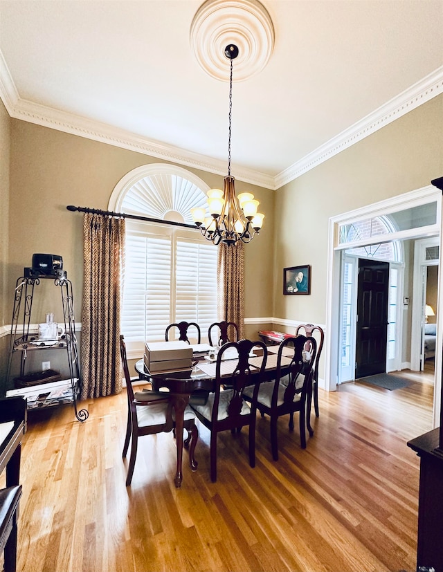 dining room featuring crown molding, wood-type flooring, and a notable chandelier