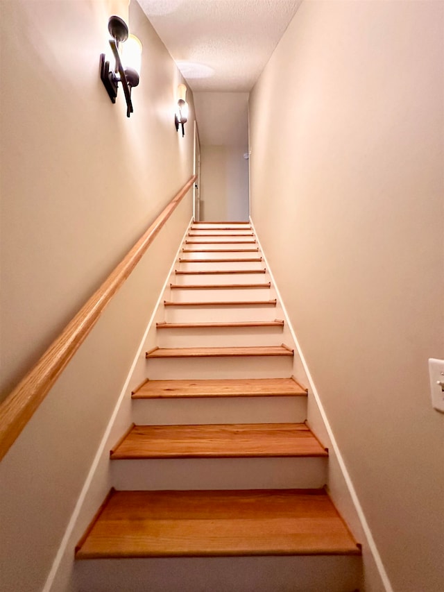 stairway featuring a textured ceiling