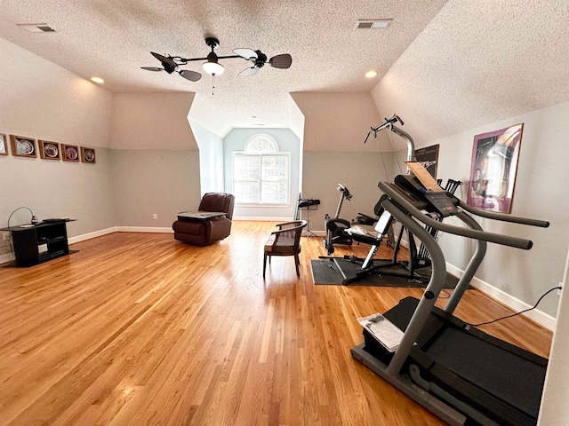 exercise area with wood-type flooring, a textured ceiling, vaulted ceiling, and ceiling fan