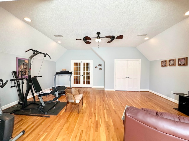 exercise area with french doors, a textured ceiling, ceiling fan, hardwood / wood-style flooring, and lofted ceiling