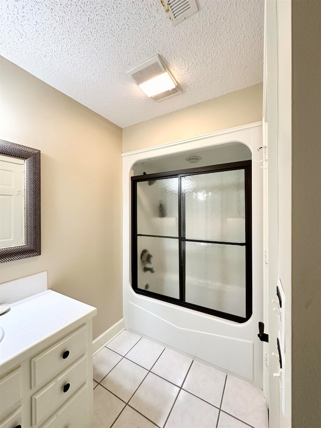 bathroom featuring tile patterned flooring, vanity, bath / shower combo with glass door, and a textured ceiling