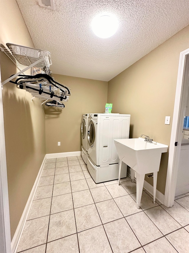 laundry room with light tile patterned flooring, sink, a textured ceiling, and washing machine and clothes dryer