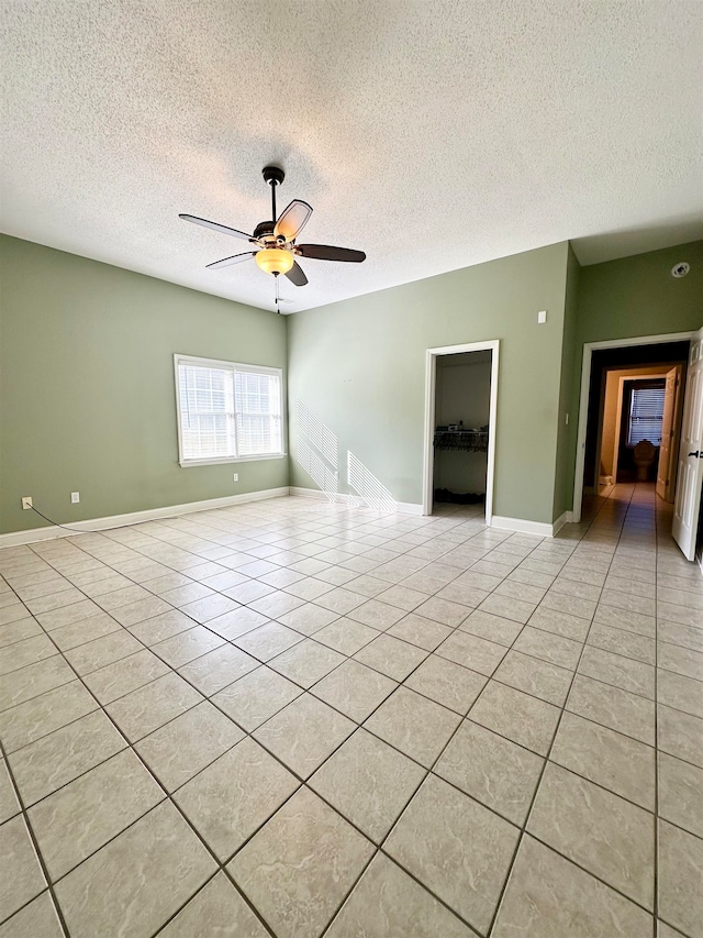 unfurnished room with ceiling fan, light tile patterned flooring, and a textured ceiling