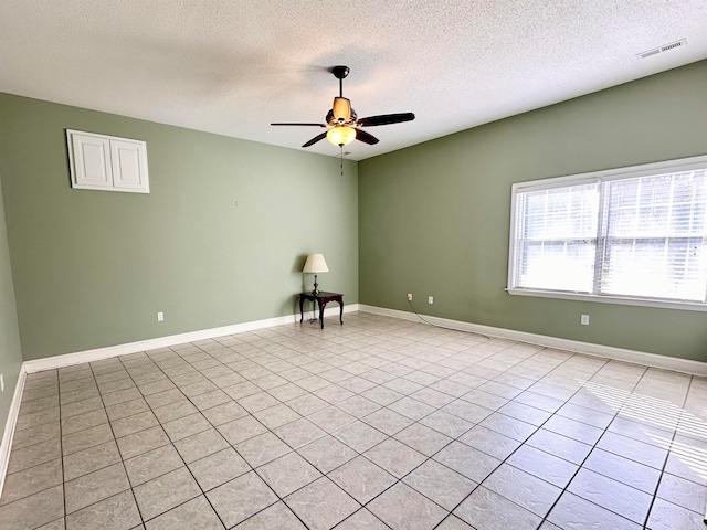 empty room featuring ceiling fan, light tile patterned floors, and a textured ceiling