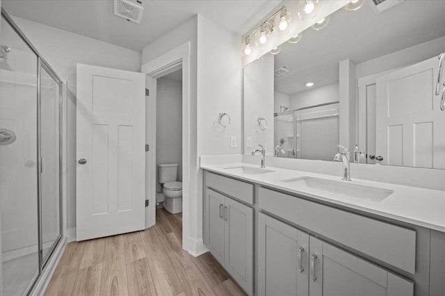 bathroom with hardwood / wood-style flooring, vanity, toilet, and a shower with door