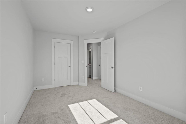 unfurnished bedroom featuring light carpet and a closet