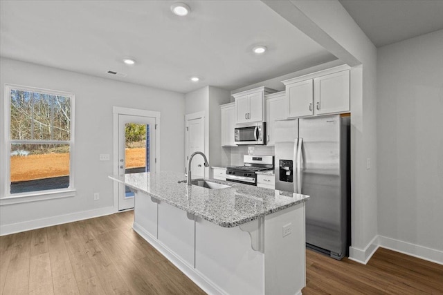 kitchen featuring sink, a kitchen breakfast bar, stainless steel appliances, a kitchen island with sink, and white cabinets