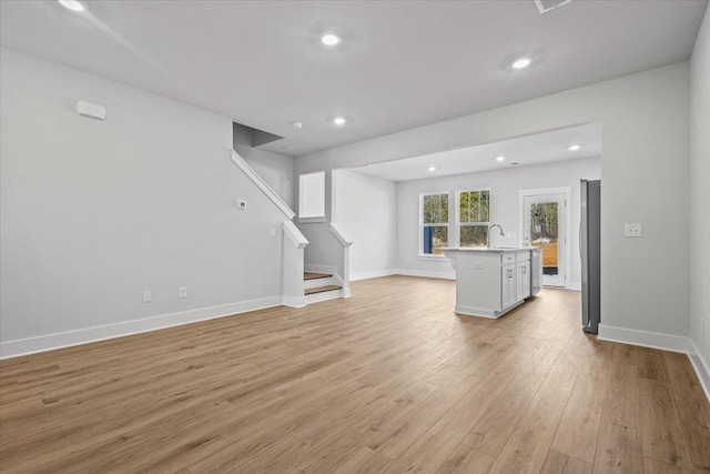 unfurnished living room with sink and light wood-type flooring