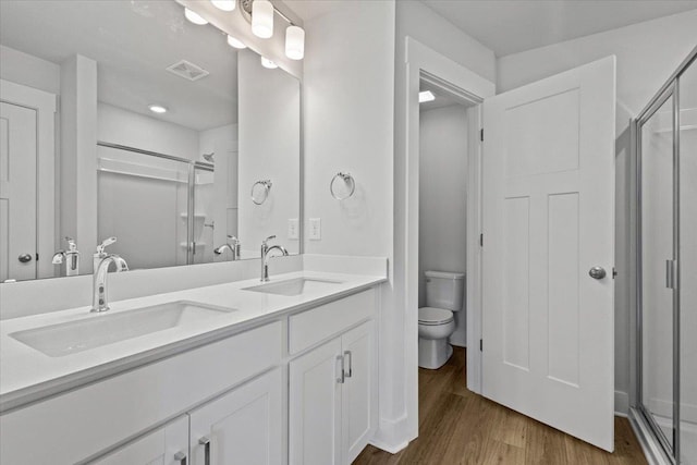 bathroom featuring wood-type flooring, toilet, an enclosed shower, and vanity