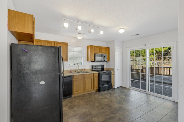 kitchen with black appliances, plenty of natural light, sink, and a textured ceiling