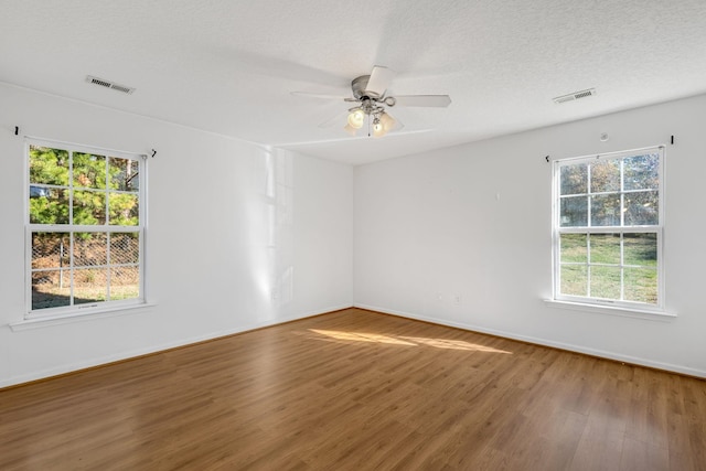 unfurnished room featuring ceiling fan, a healthy amount of sunlight, a textured ceiling, and hardwood / wood-style flooring