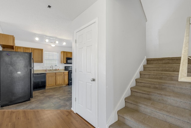 stairway with a textured ceiling, hardwood / wood-style flooring, and sink