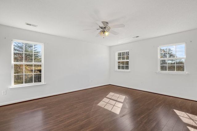 spare room with ceiling fan, a healthy amount of sunlight, and dark hardwood / wood-style flooring