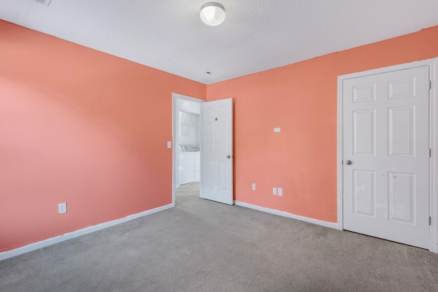 unfurnished bedroom featuring a textured ceiling, washer and dryer, and light carpet